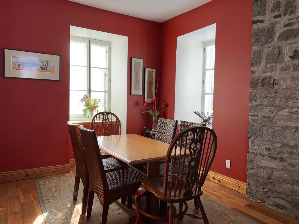 a dining room with red walls and a wooden table and chairs at Artillery view Condo (free parking) in Quebec City