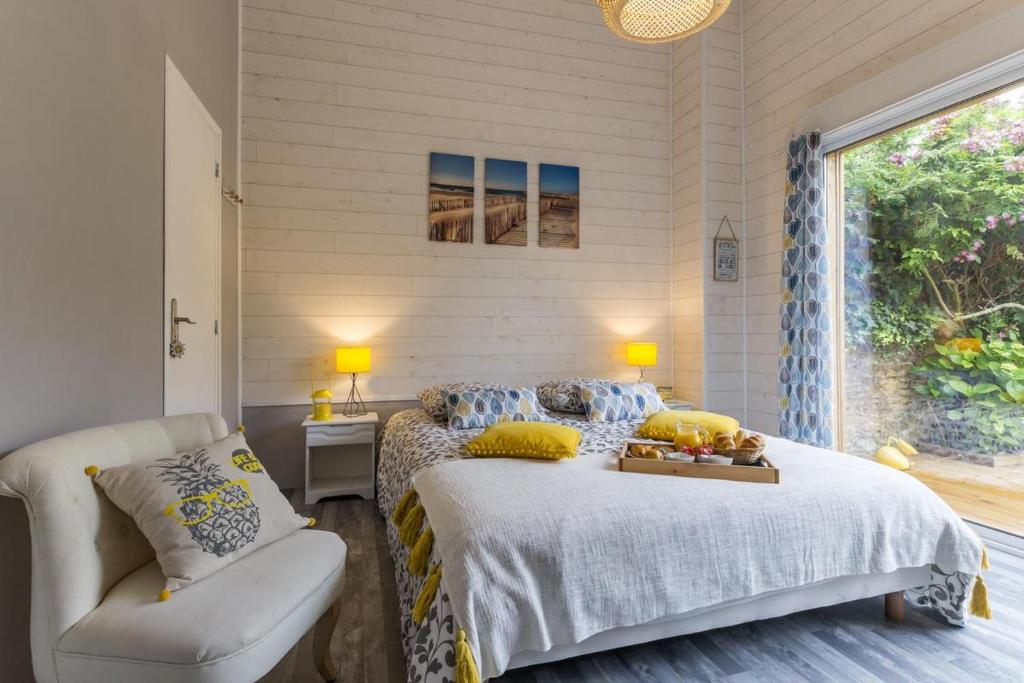 a bedroom with a bed and a chair and a window at LES PIEDS DANS L'EAU in Merville-Franceville-Plage