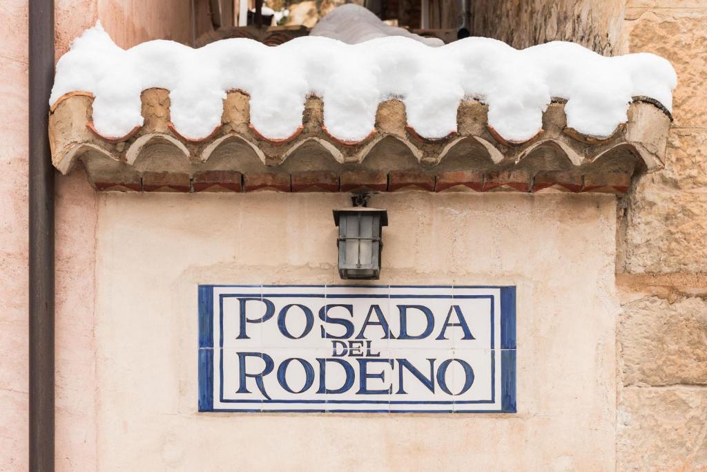 a sign on the side of a building with a snow covered roof at Posada del Rodeno in Albarracín