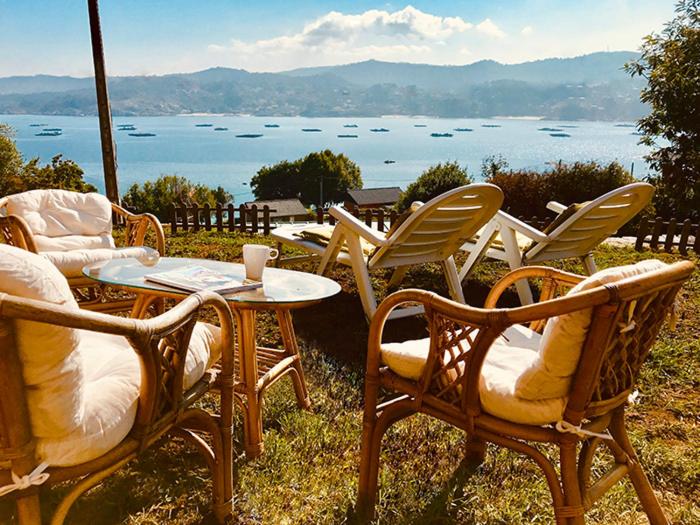 un grupo de sillas y una mesa con vistas al agua en Casa La Batea, en Aldán