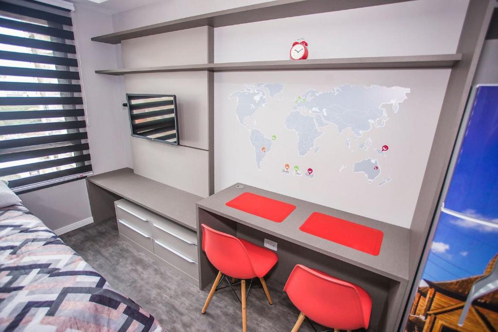 1 Schlafzimmer mit einem Schreibtisch und 2 roten Stühlen in der Unterkunft Studio Central prox a Rua XV de Novembro - ALL1311 in Curitiba