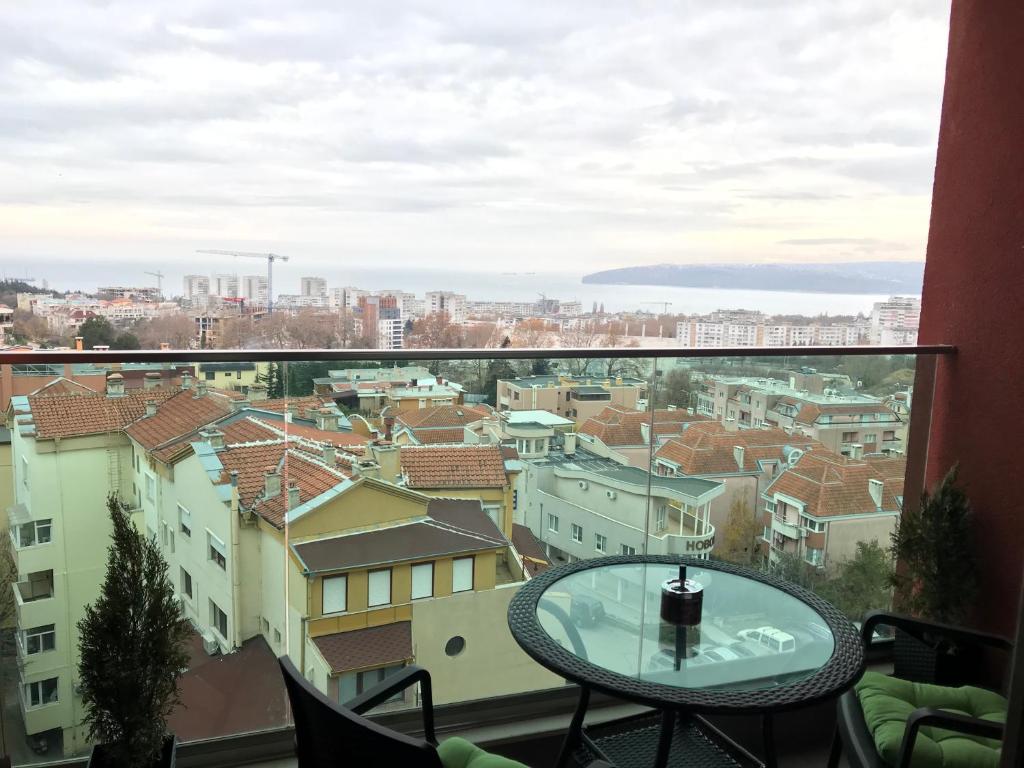 Breathtaking sea view apartment في مدينة فارنا: بلكونه مع طاوله واطلاله على مدينه
