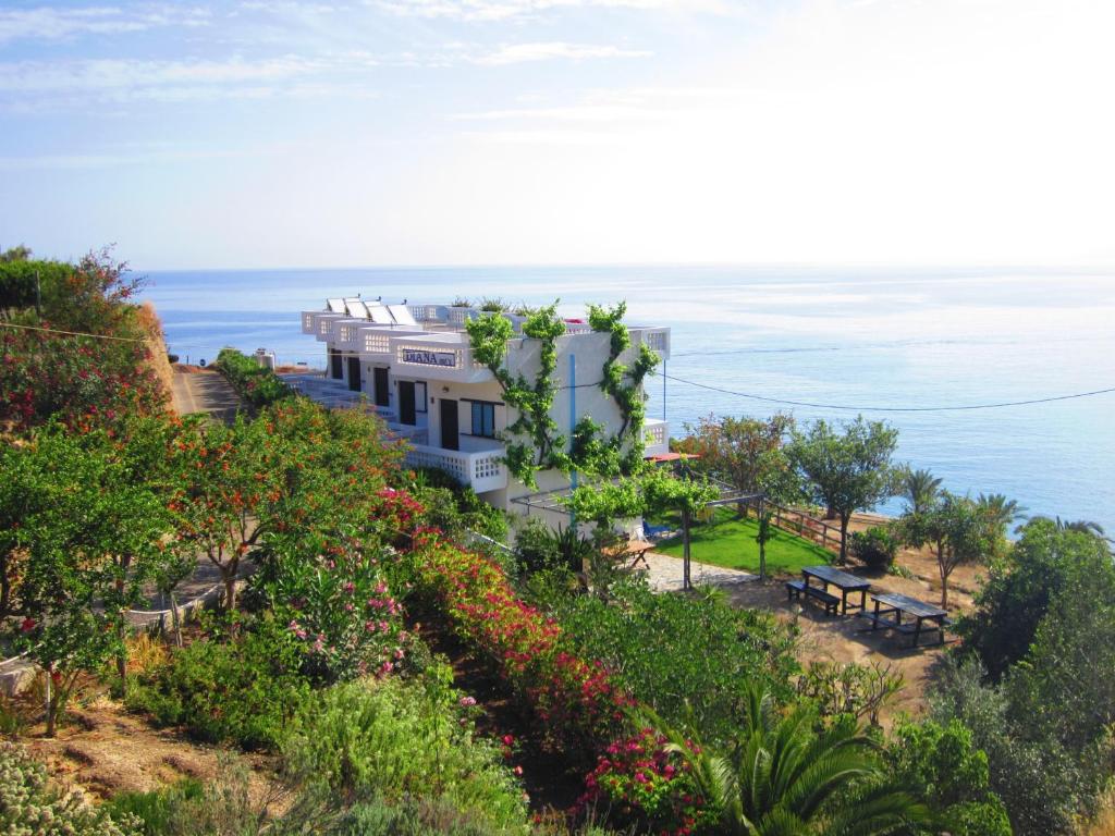 a house on a hill with the ocean in the background at Diana Apartments in Agia Pelagia