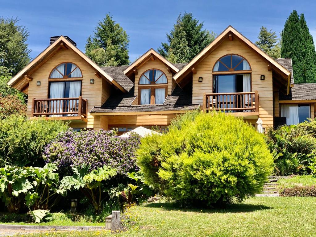 una casa de madera con un paisaje en Hotel & Apart Hotel Monte Verde, en Pucón