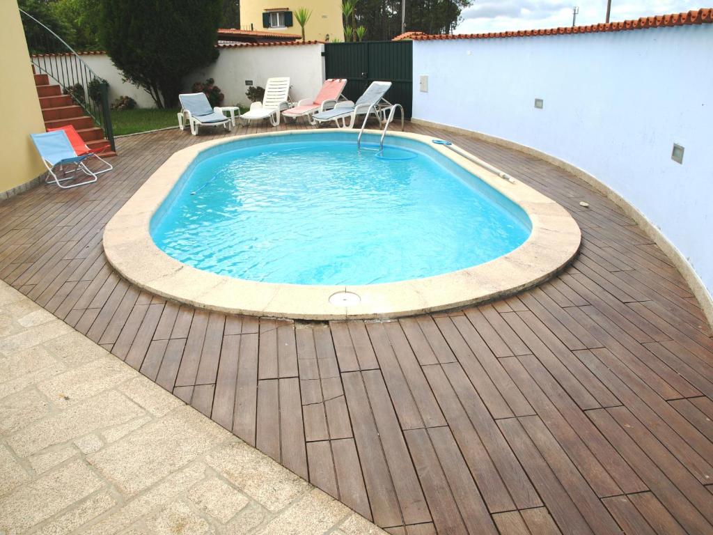 a swimming pool on a wooden deck with chairs around it at Villa Moino in Barcelos