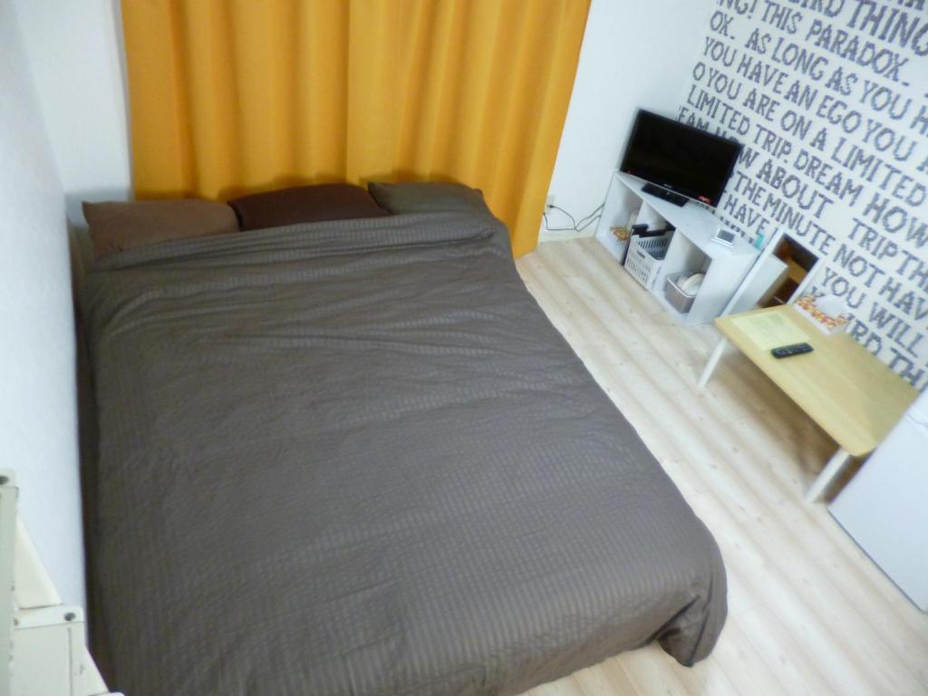 1 dormitorio con 1 cama y TV en THE MICKEY CARLTON Ohashi 101, en Shiobaru