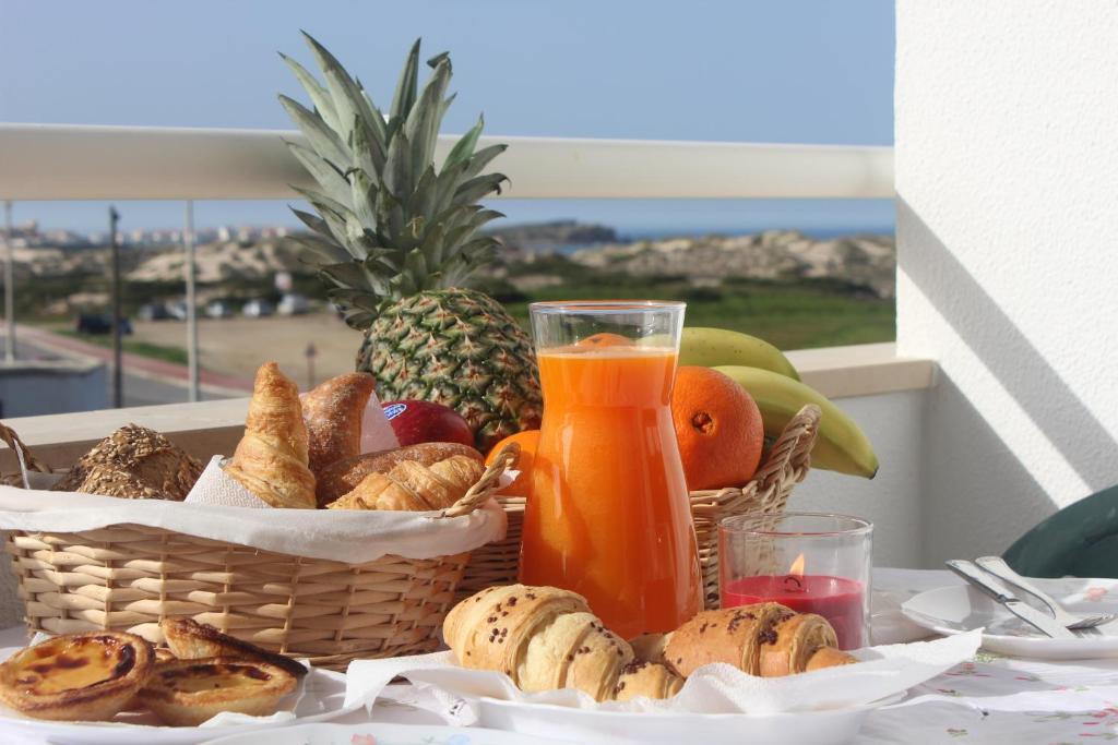 een mand met brood en fruit en een glas sinaasappelsap bij Filipe´s House in Baleal