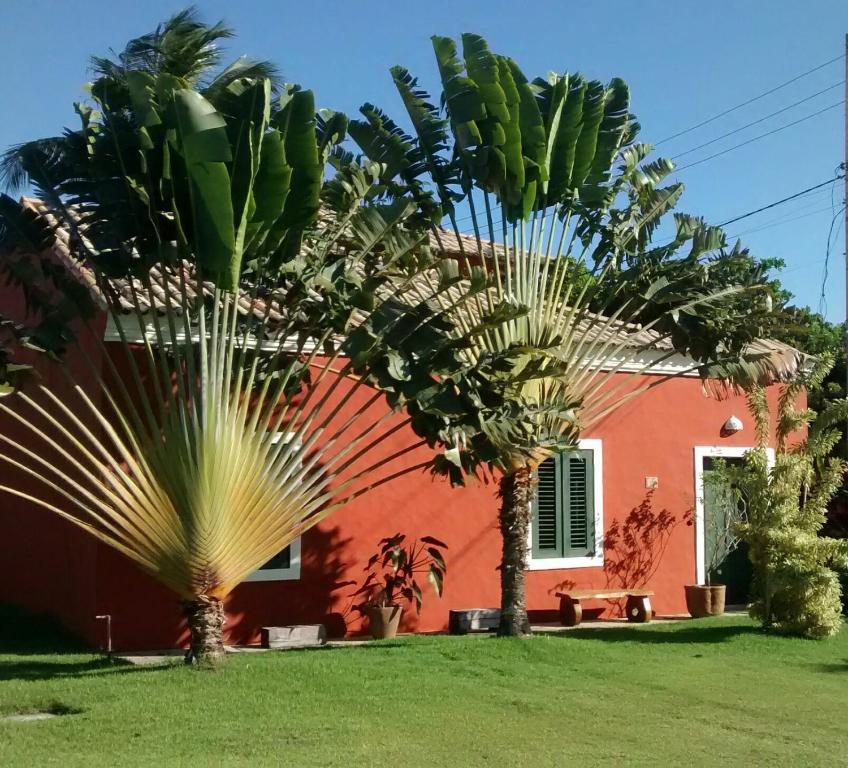 a red house with palm trees in front of it at Casa Vila Do Outeiro in Praia do Espelho