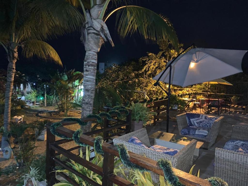 a patio with chairs and an umbrella and a palm tree at Villa Mistika in Zorritos