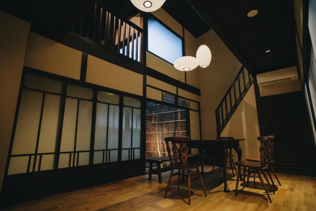 una sala da pranzo con tavolo, sedie e finestre di 七条みやび Nanajo Miyabi Inn a Kyoto