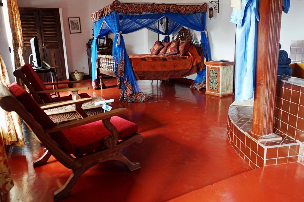 فندق Zanzibar Palace في مدينة زنجبار: غرفة معيشة فيها سرير وكرسي