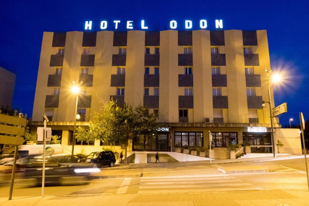 un edificio de hotel odoren por la noche con coches pasando por él en Hotel Odon, en Cocentaina