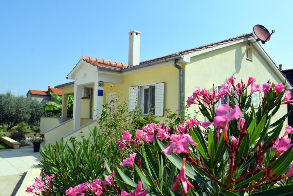 une maison avec des fleurs roses devant elle dans l'établissement Villa Danny ****, à Dobropoljana