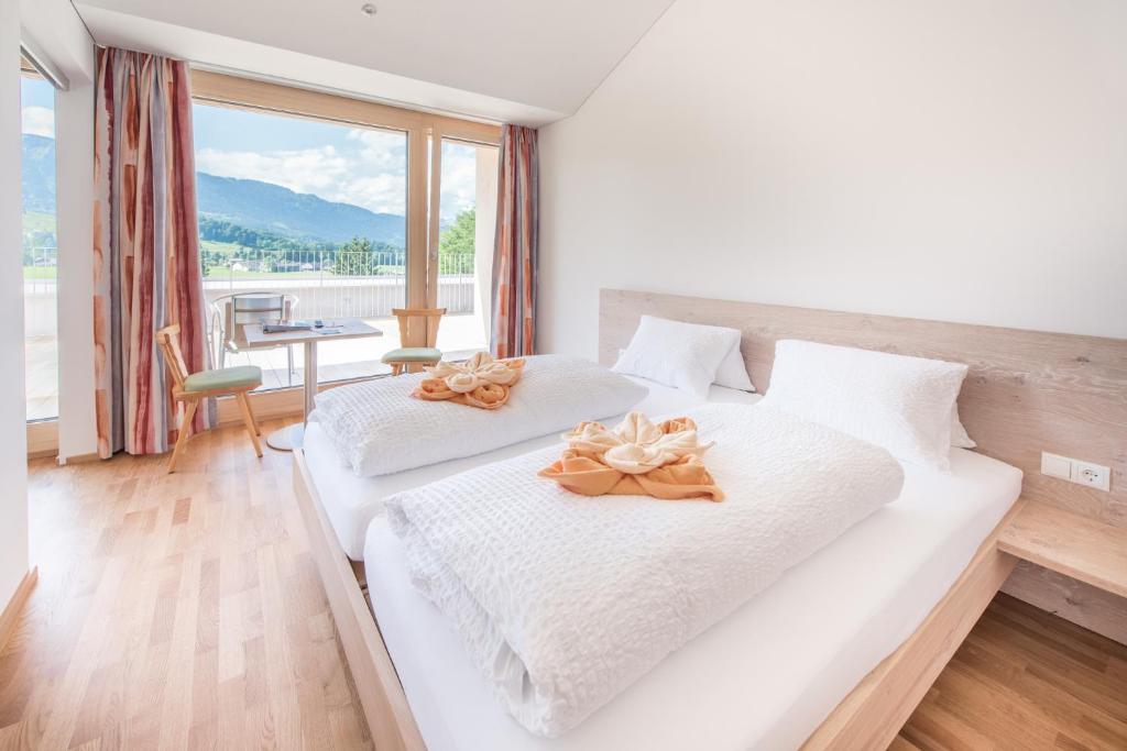 two beds in a room with a large window at Hotel Gasthof Adler in Lingenau