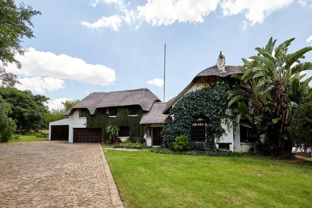 a large white house with a thatched roof at 41 Ridge- self catering cottages in Midrand
