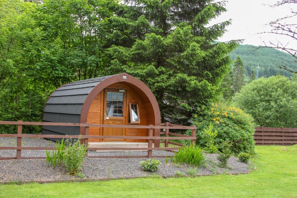 a small dome tent in a garden with a fence at Glamping Hut - By The Way Campsite in Tyndrum