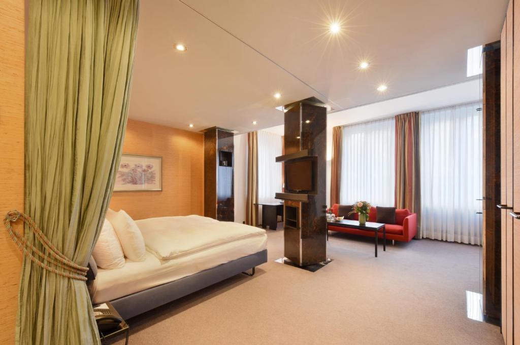 a hotel room with a bed and a living room at Glärnischhof by TRINITY in Zürich