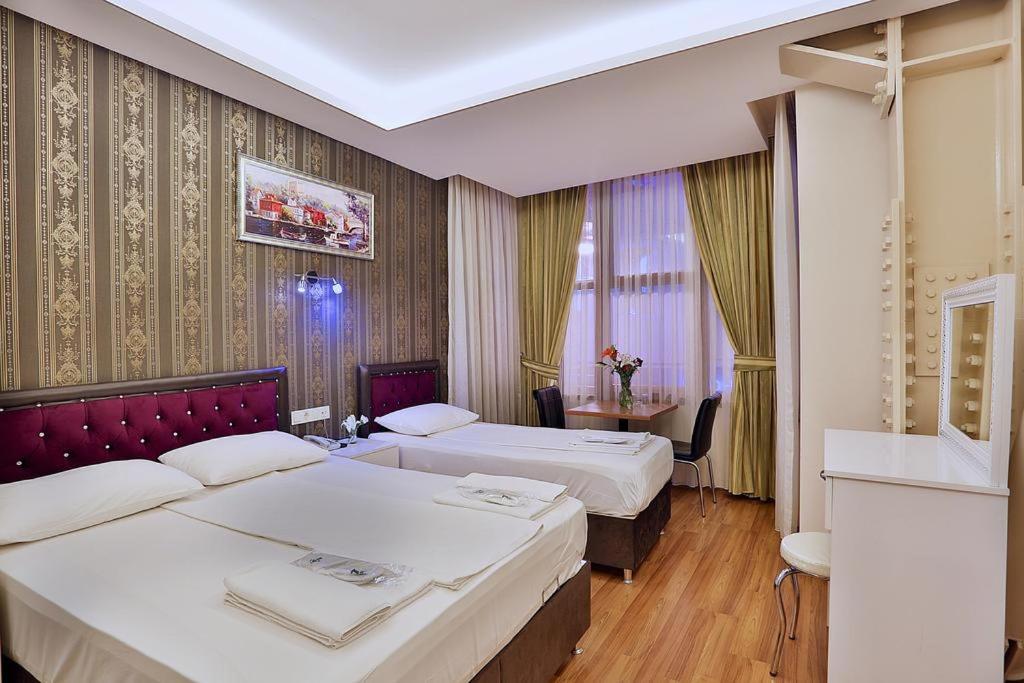 a hotel room with two beds and a table at Gh Suites Taxim Hotel in Istanbul