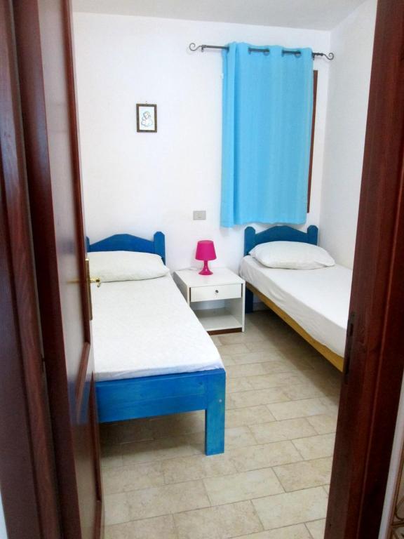 a room with two beds and a blue curtain at Sardinia Yellow House in Solanas