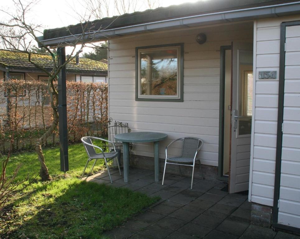 Schoorldam的住宿－Rekerlanden 154，房屋前设有带2把椅子和1张桌子的庭院。