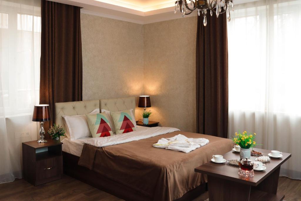 1 dormitorio con 1 cama grande y 2 mesas en De'Mar Hotel en Bishkek
