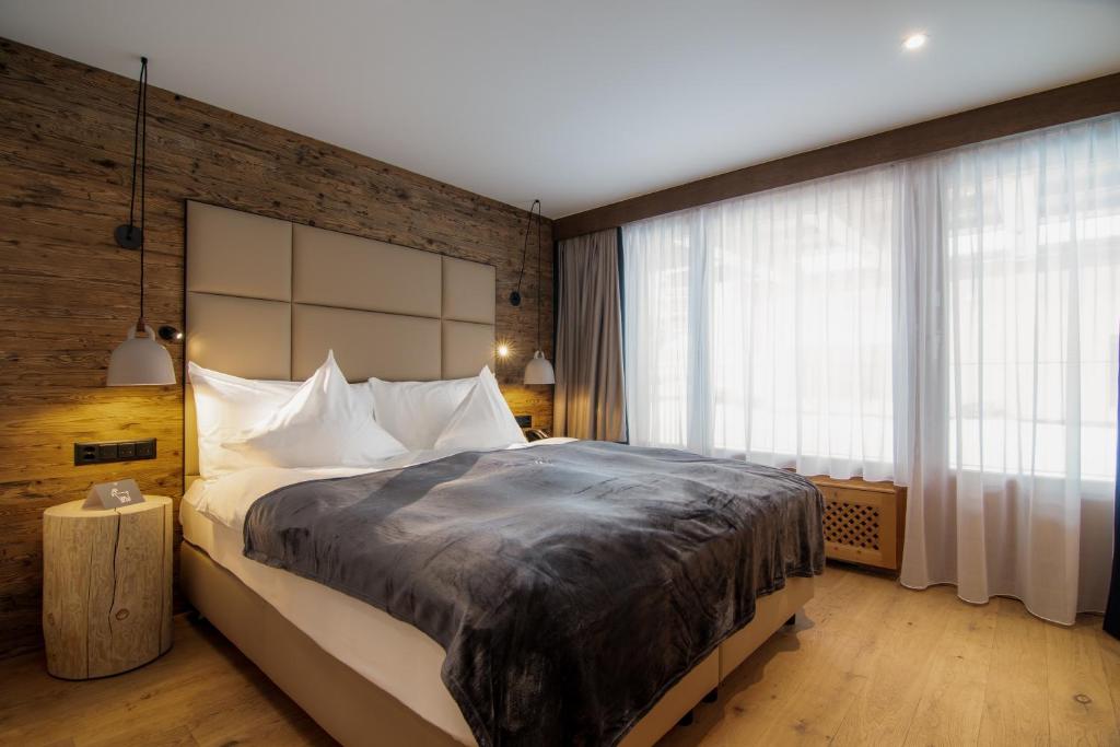 a bedroom with a large bed and a brick wall at Walliserhof Grand-Hotel & Spa Relais & Châteaux in Saas-Fee