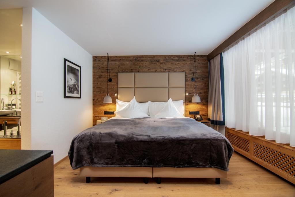 a bedroom with a large bed and a brick wall at Walliserhof Grand-Hotel & Spa Relais & Châteaux in Saas-Fee