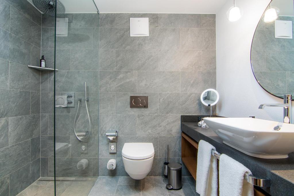a bathroom with a sink and a toilet and a shower at Walliserhof Grand-Hotel & Spa Relais & Châteaux in Saas-Fee