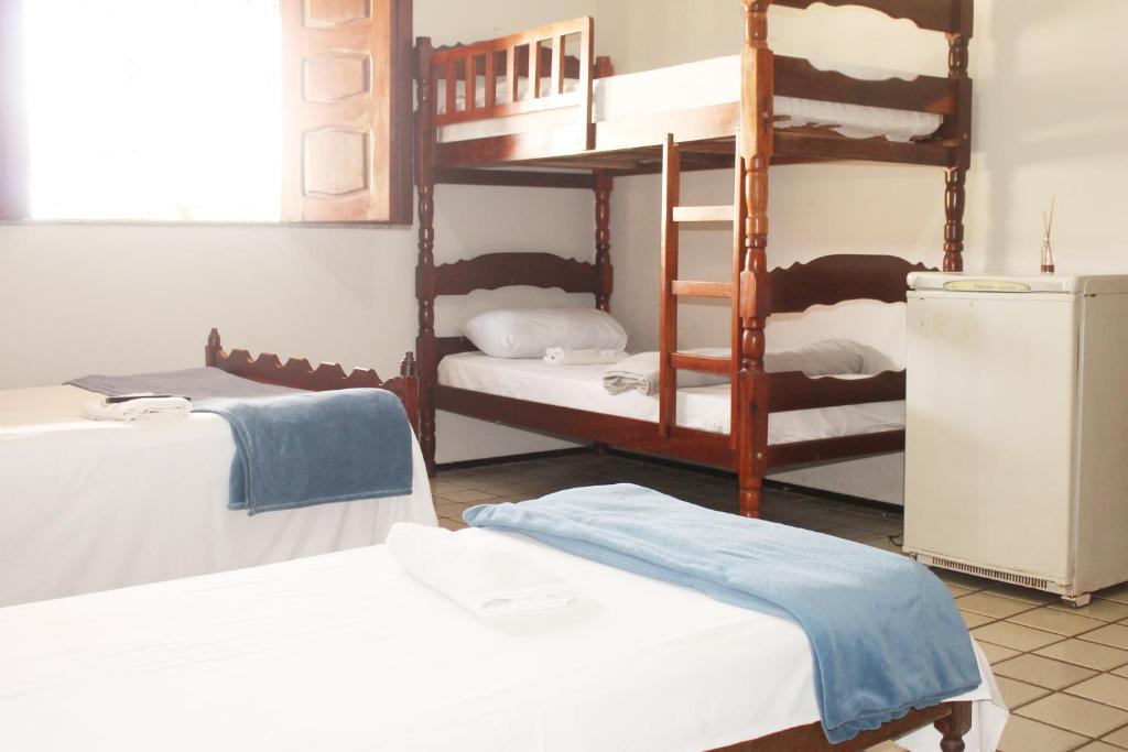 a room with three bunk beds and a refrigerator at Hotel Pousada Calhau in São Luís