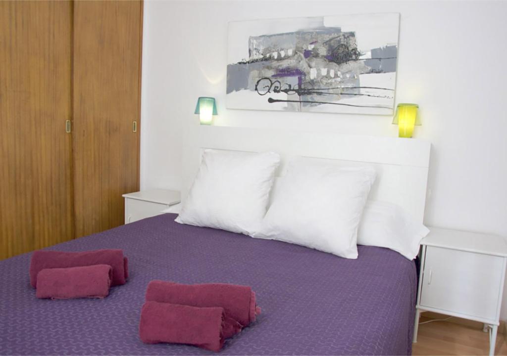 um quarto com uma cama com duas almofadas vermelhas em Apartment carrer d'Olesa em Barcelona