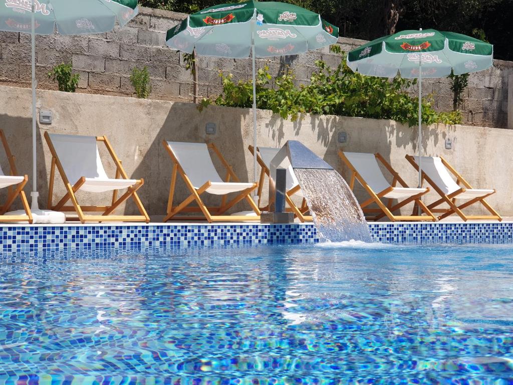 a group of chairs and umbrellas next to a swimming pool at GREJM Family Apartments in Petrovac na Moru