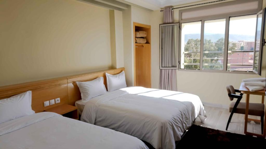 um quarto de hotel com duas camas e uma janela em Hotel Golden Flora em Beni Mellal