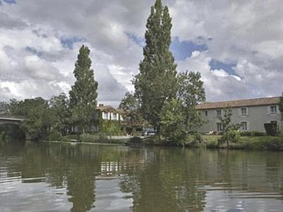 three trees in the water next to a building at Logis Auberge De La Riviere in Velluire