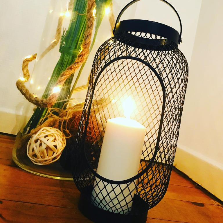 une bougie dans un panier métallique à côté d'un vase dans l'établissement Charmant 2 pièces - Centre ville de Melun, à Melun
