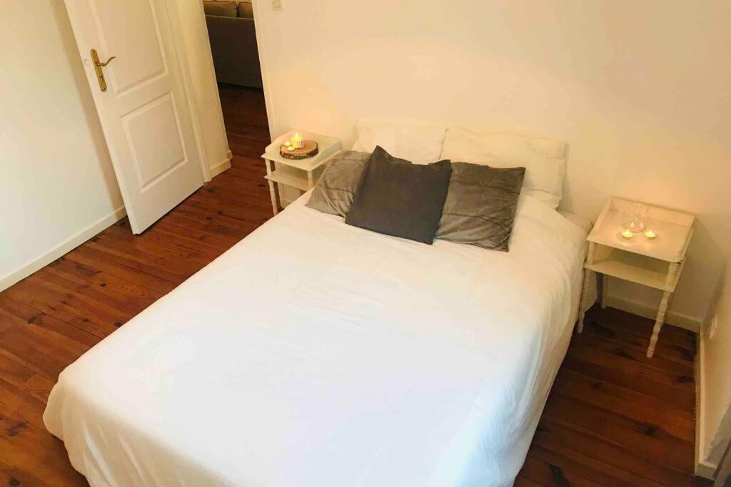 - une chambre avec un lit blanc et 2 tables dans l'établissement Charmant 2 pièces - Centre ville de Melun, à Melun