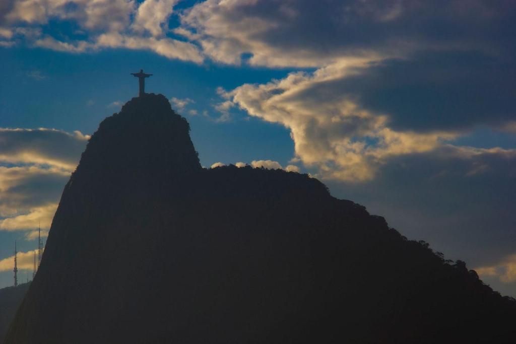 une croix au sommet d'une montagne avec un ciel nuageux dans l'établissement BestHostRio - Vista incrível no bairro da Urca, à Rio de Janeiro