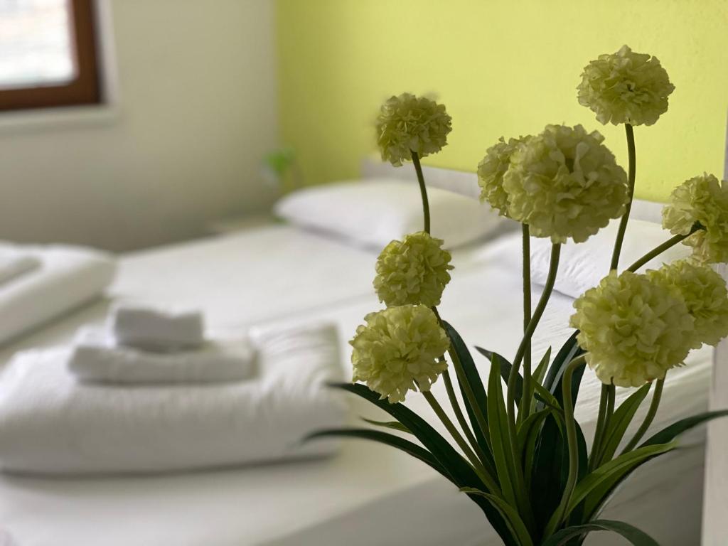 a vase filled with white flowers on a bed at Pansion Fočin Han in Sarajevo