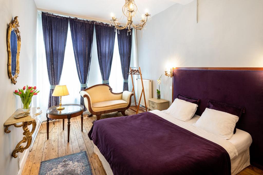 een slaapkamer met een paars bed en een stoel bij L'atelier de Hugo in Brussel