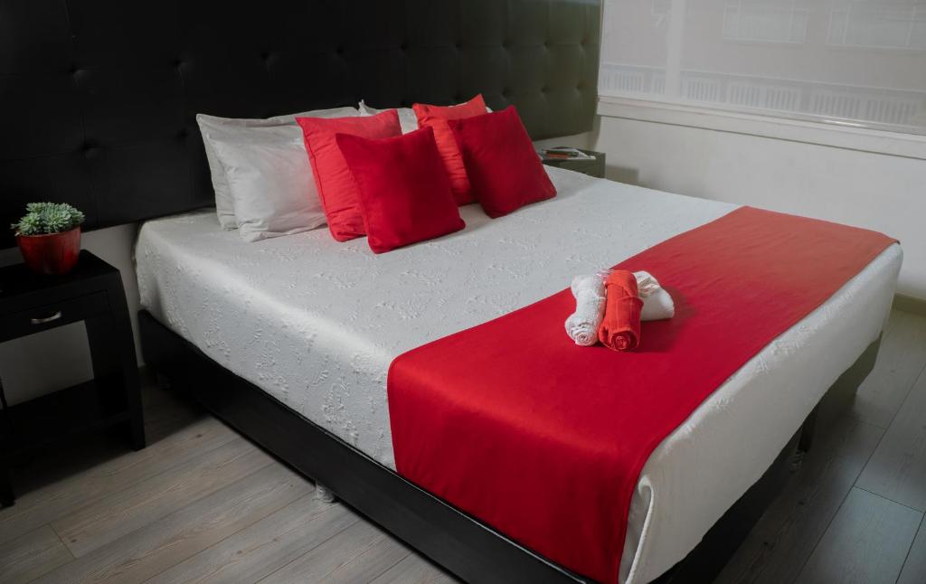 a bed with two stuffed animals on a red blanket at Hotel Metro 26 in Bogotá