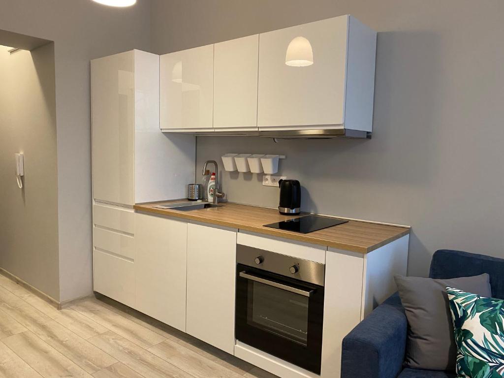 małą kuchnię z białymi szafkami i niebieską kanapą w obiekcie Apartament URBAN JUNGLE! w Poznaniu