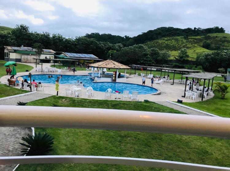 una gran piscina con gente sentada a su alrededor en Apartamento/Flat - Condominio Village - Aldeia das Águas Park Resort., en Barra do Piraí