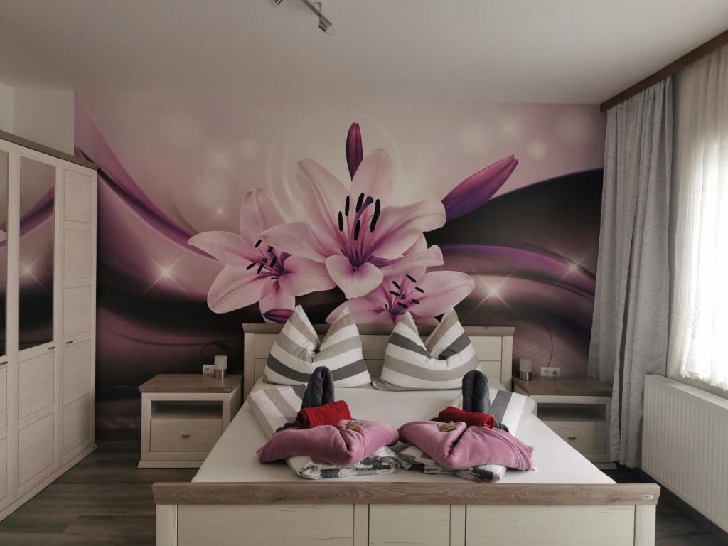 ein Schlafzimmer mit einem Bett mit rosa Blumen an der Wand in der Unterkunft Appartement zur Therme in Bad Mitterndorf