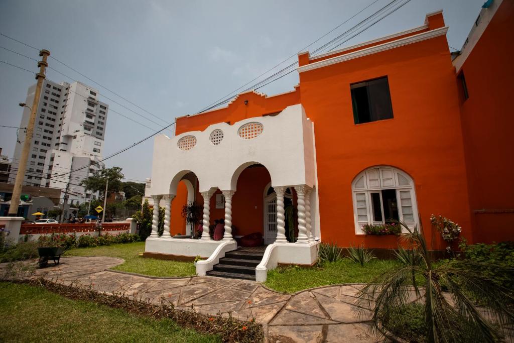 an orange and white building with stairs in the yard at Great Partners hostel in Lima