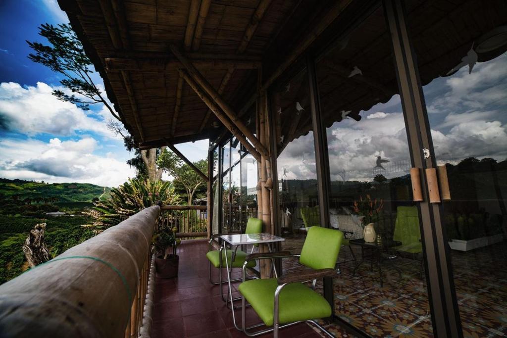 a patio with green chairs and a table on a balcony at Hacienda Guayabal in Chinchiná