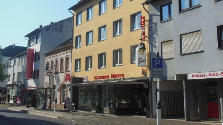 a tall yellow building on a city street at Central Hotel in Troisdorf