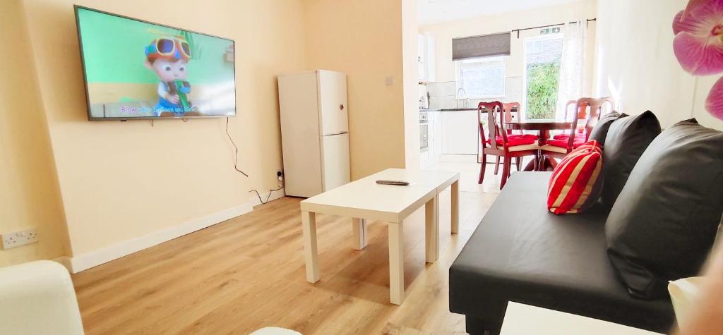 a living room with a couch and a tv on a wall at Apple Garden A-2 in London