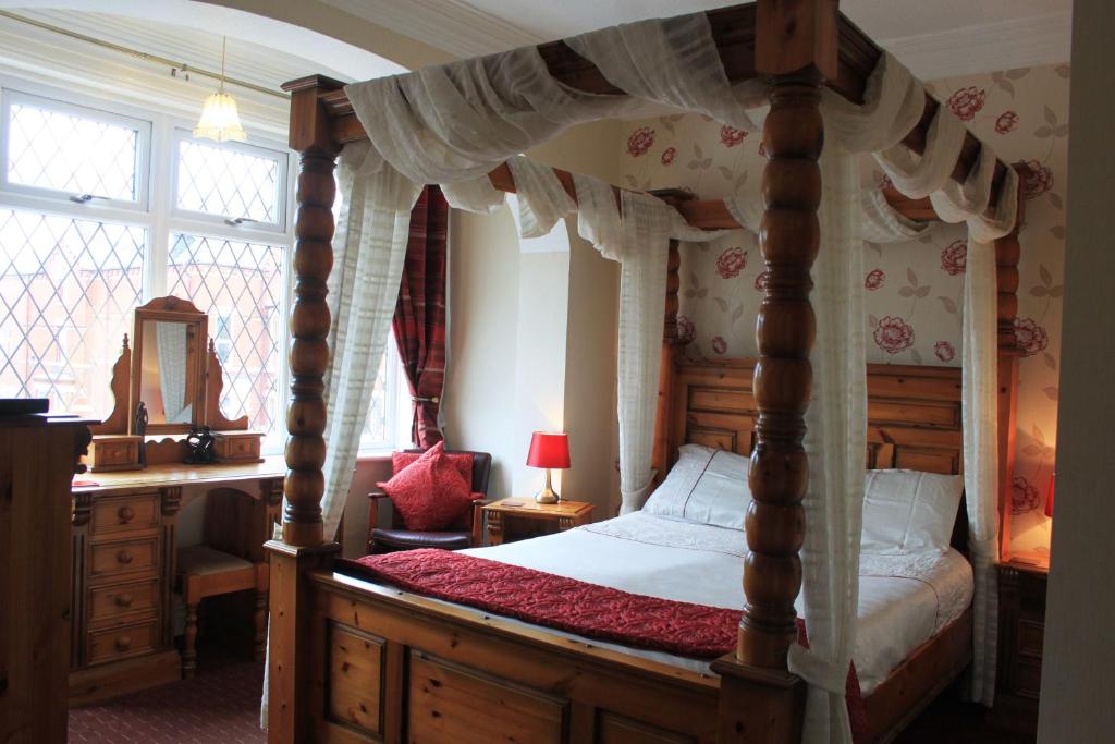 1 dormitorio con cama con dosel y escritorio en The Belmont, en Bridlington