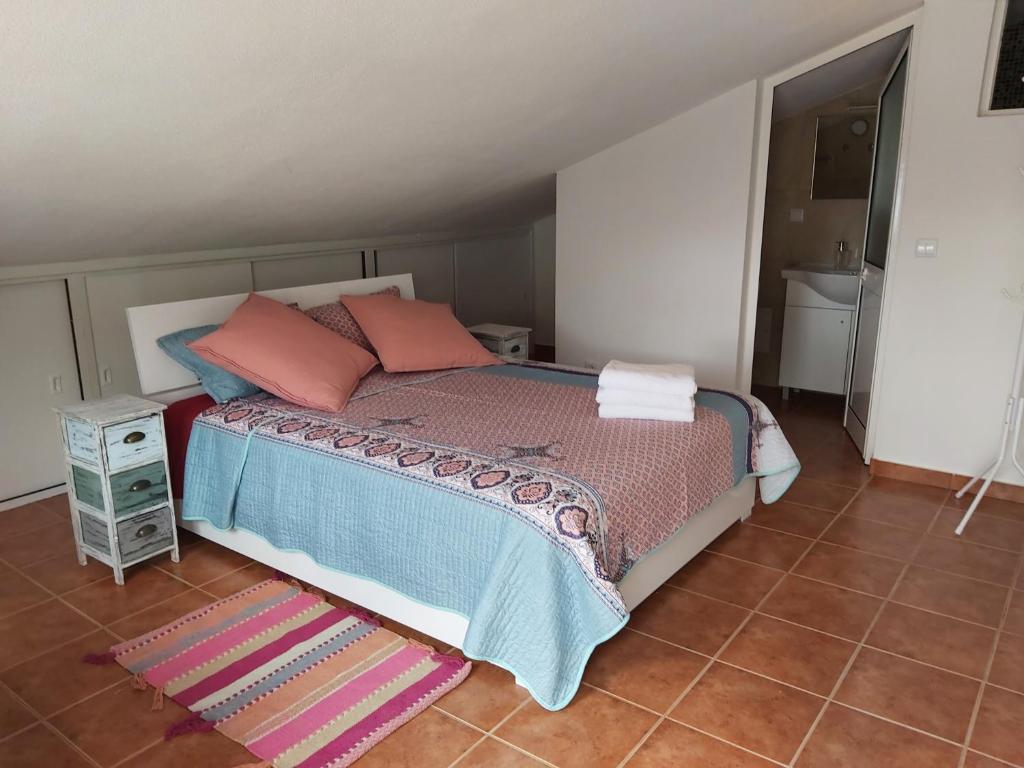 um quarto com uma cama com almofadas cor-de-rosa e um tapete em Tabua Village Nature Lovers & Sea #5 em Ribeira Brava