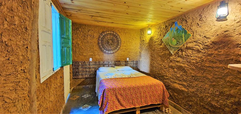 een slaapkamer met een bed in een stenen muur bij Casa do Sertão - Vila Aju in Aracaju