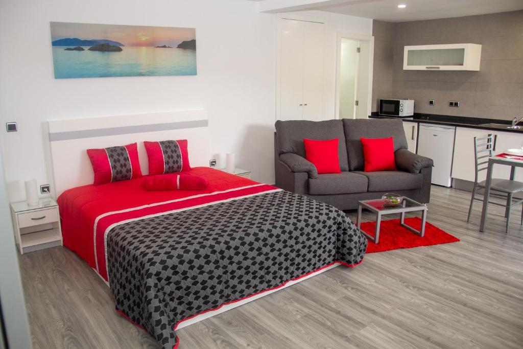 een slaapkamer met een rood bed en een bank bij Amoreira House in Calheta